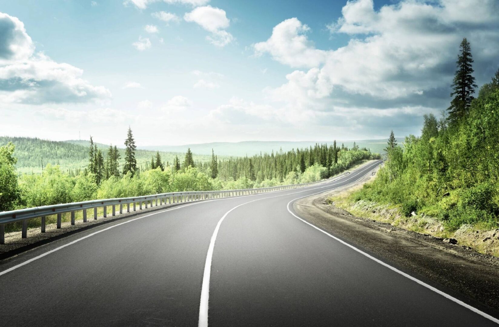 A road with trees and clouds in the background