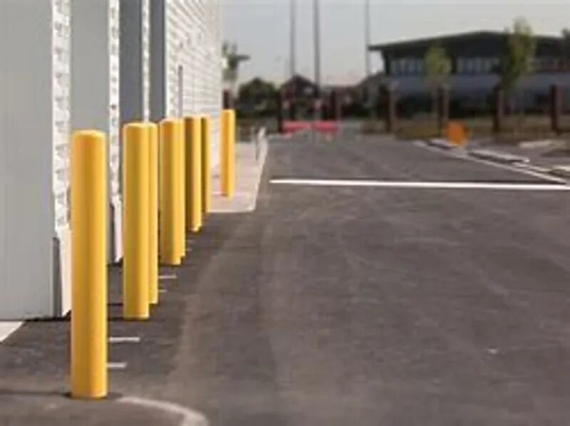 A parking lot with yellow posts on the side of it.